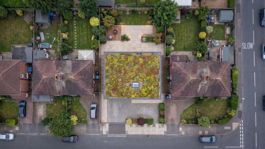 AI-generated top-down aerial view of a contemporary house in a UK suburban setting, with a biodiverse flat roof, showing its footprint, garden layout and relationship to neighbouring brick homes and surrounding residential plots.