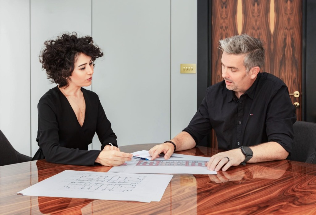 One RPTI chartered town planner and one RIBA chartered architect in a professional consultation over building plans, with focus on teamwork and collaboration in project planning.