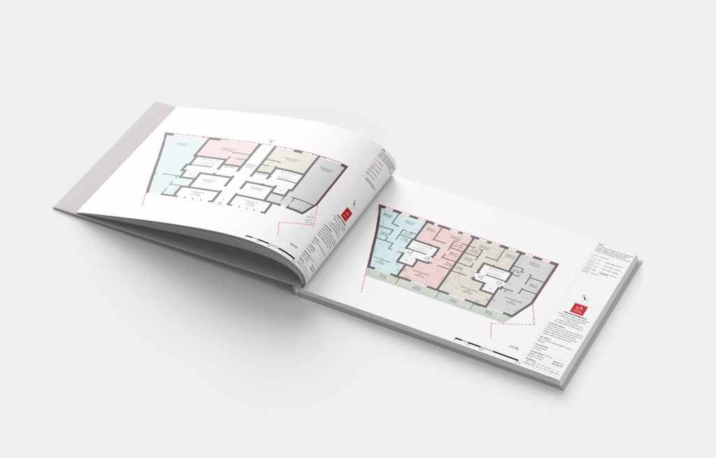 Open architectural floor plan book on a white surface showcasing detailed building layouts in various colors, indicating the meticulous process of planning and design in architecture.