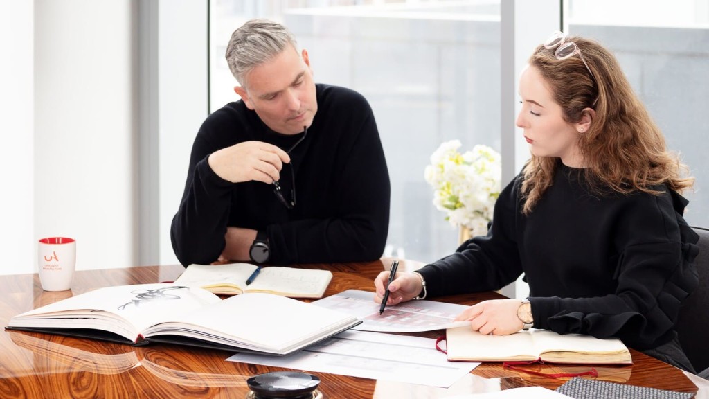 Two of Urbanist Architecture's architects engaging in a collaborative discussion over building plans at a modern office table, illustrating the meticulous planning and teamwork involved in architectural design and project development.