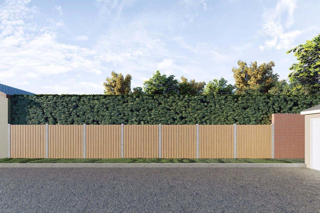 An empty parcel of land enclosed by a wooden fence and a brick wall, with the space overgrown with dense, leafy vegetation, illustrating potential for land development or green space in an urban setting.