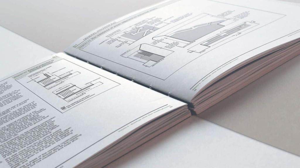 Open architectural plan book displaying detailed barn conversion blueprints and cross-sections, with annotations and measurements, symbolising meticulous design and planning in architecture on a clean white background.