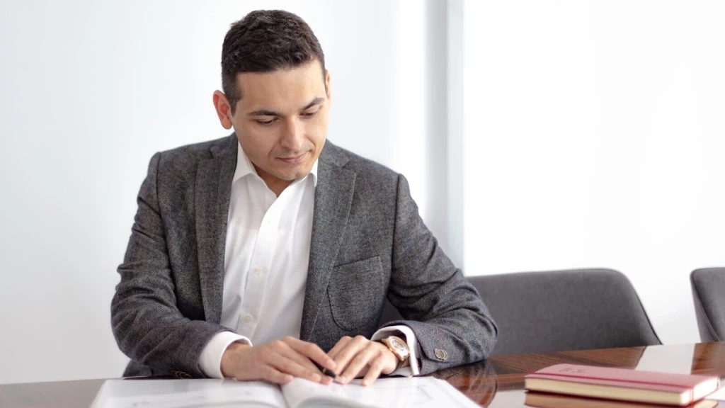 Professional man reviewing planning and housing policy documents at a meeting table, calling for political accountability on unspent developer contributions.