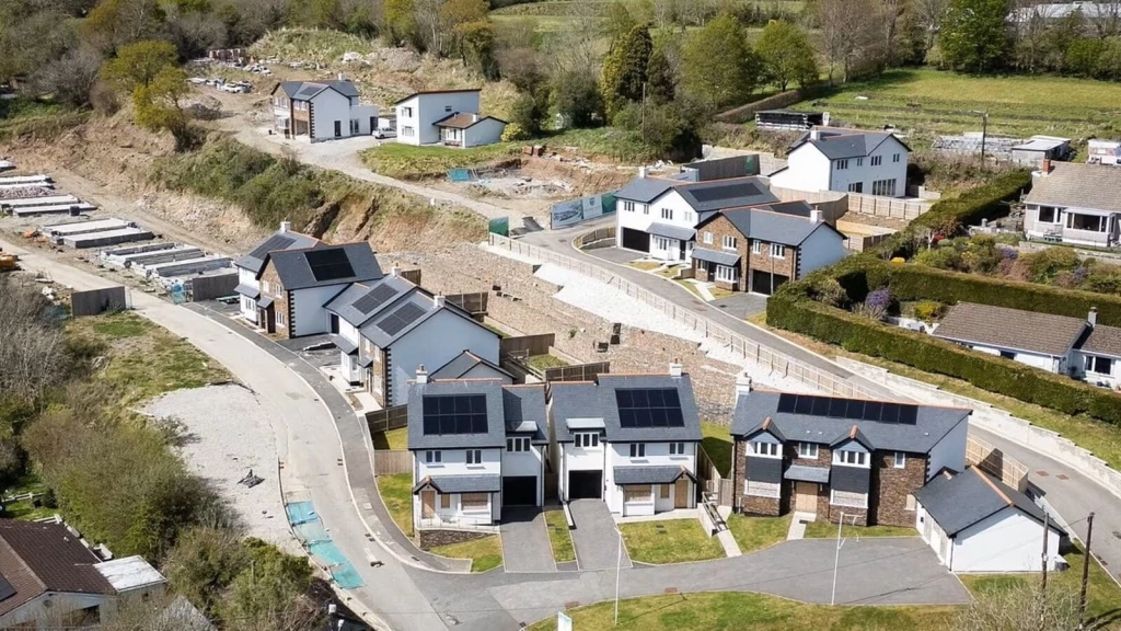 Aerial view of new UK housing estate with unfinished plots and roads, representing stalled development and need for systemic planning reform.