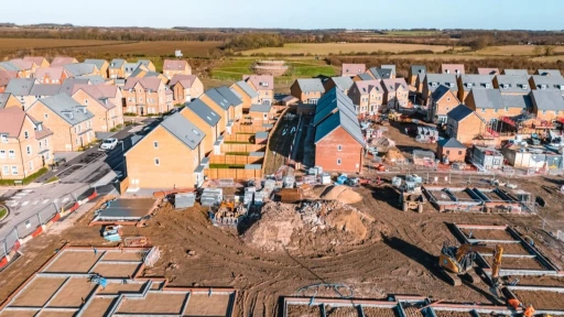 Aerial view of a new UK housing development under construction with unfinished roads and empty building plots, symbolising unspent developer contributions and missing local infrastructure.