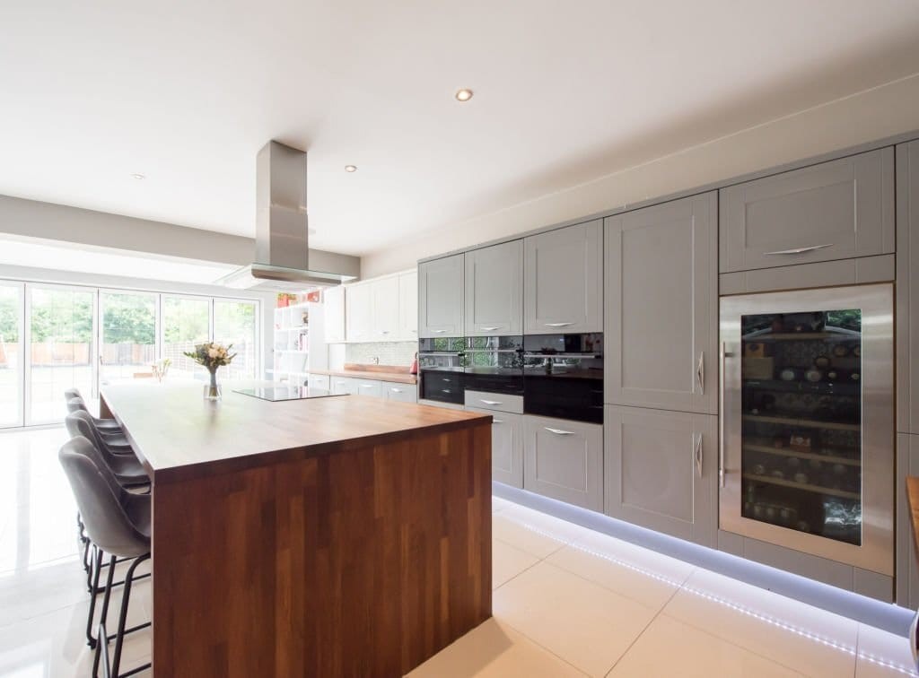 With the development of a large rear extension with custom made bifold doors leading into the sunny garden, a modern kitchen was made bigger with the main feature of a large dark wood island, double oven fitted into the grey cupboards and a large wine cellar
