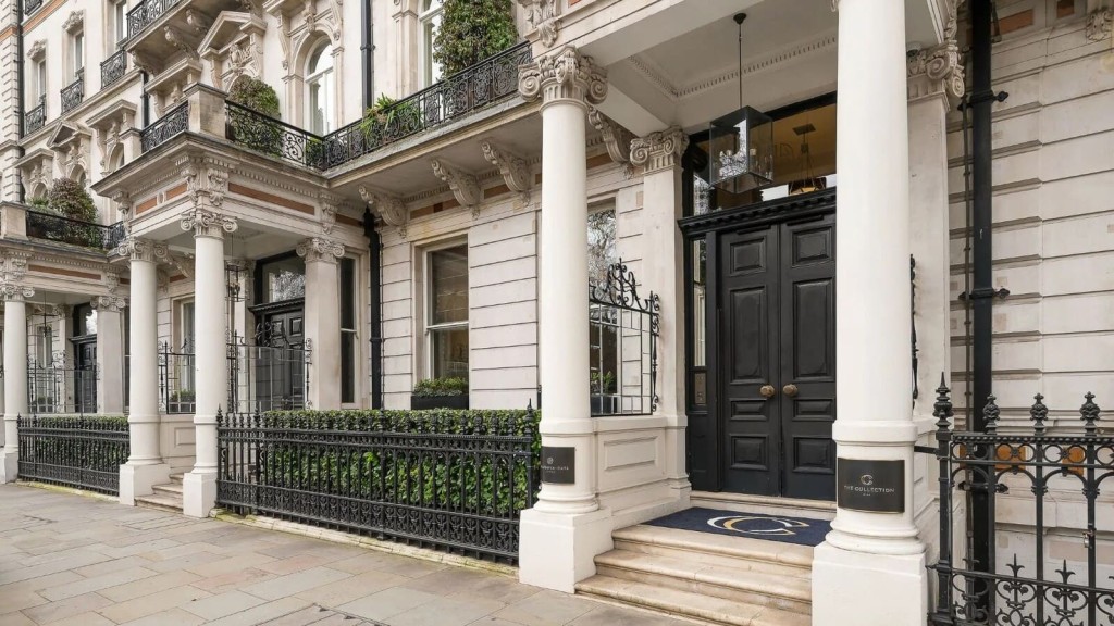 Exterior of a grand Grade II listed building in London featuring ornate columns, black double doors, and intricate wrought-iron fencing. This historical facade showcases the architectural beauty of listed properties, emphasising the importance of preservation in heritage buildings. An essential visual for those interested in purchasing or restoring listed properties in the UK, with a focus on maintaining original design elements.