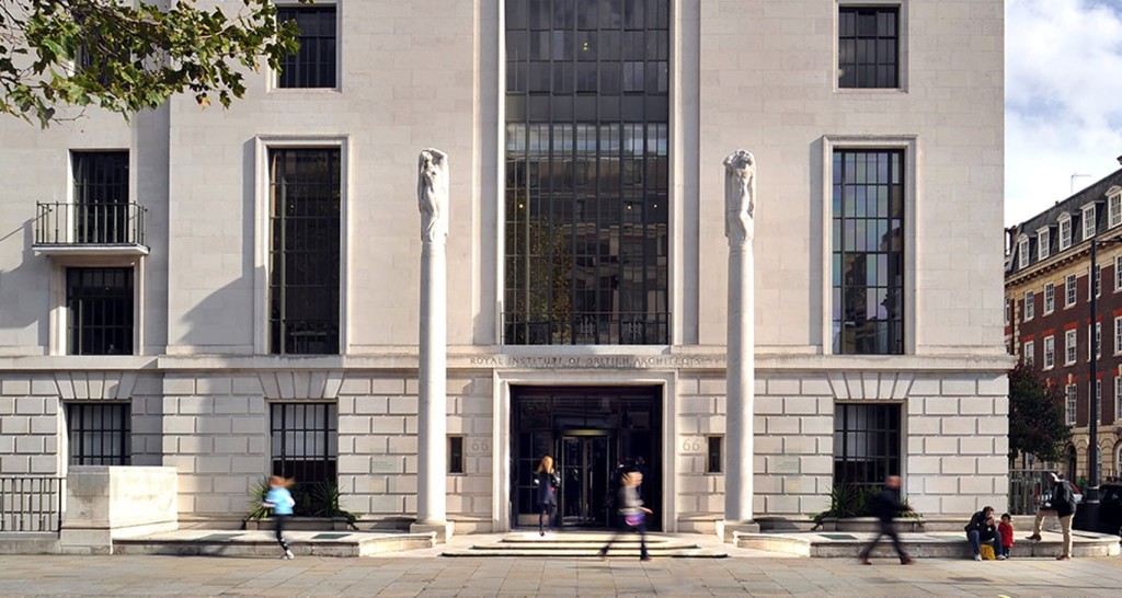 Facade of the Royal Institute of British Architects building with its iconic tall windows and classical statues, people walking by the entrance on a sunny day.