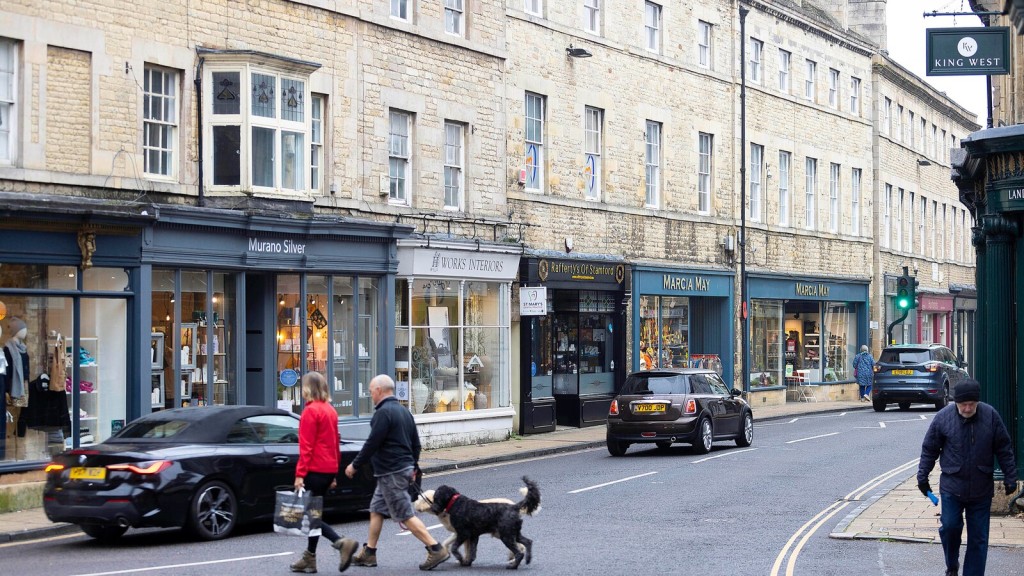 Street view of shops and pedestrians in a historic town center with cars driving past, illustrating use class g.