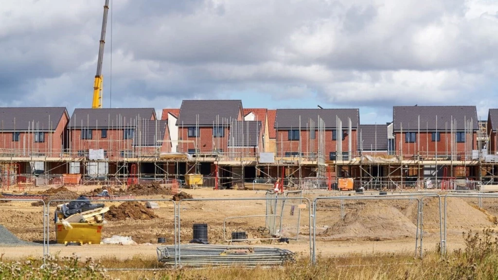 New housing under construction with scaffolding and site infrastructure, illustrating how local decisions and statutory consultees shape the determinations of planning applications within the planning system.