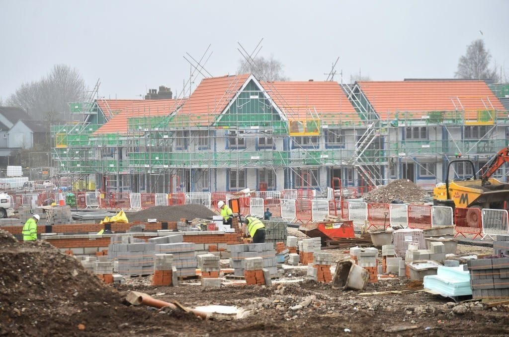 Construction site of new residential homes, highlighting the transformation of former petrol station land into valuable housing. This image illustrates the redevelopment process, with workers, scaffolding, and building materials emphasising the active progress in creating modern homes from disused spaces.