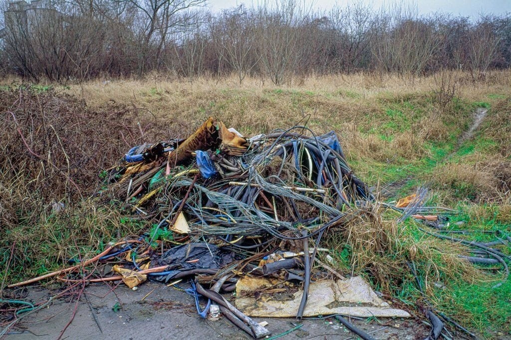 Abandoned and overgrown site with discarded cables and debris, showcasing the potential challenges and opportunities in redeveloping disused petrol stations into residential housing. This image highlights the importance of land remediation and environmental cleanup in transforming derelict spaces into valuable urban properties.
