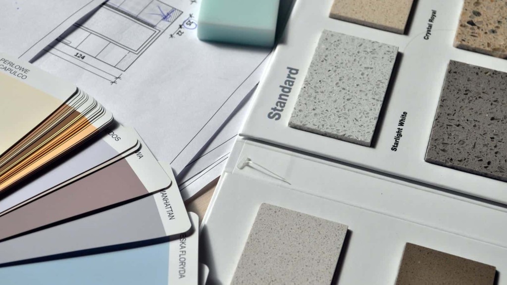 Interior design planning with a focus on material samples, featuring a palette of paint swatches in neutral colors and an array of terrazzo countertop options, alongside architectural blueprints in the background.