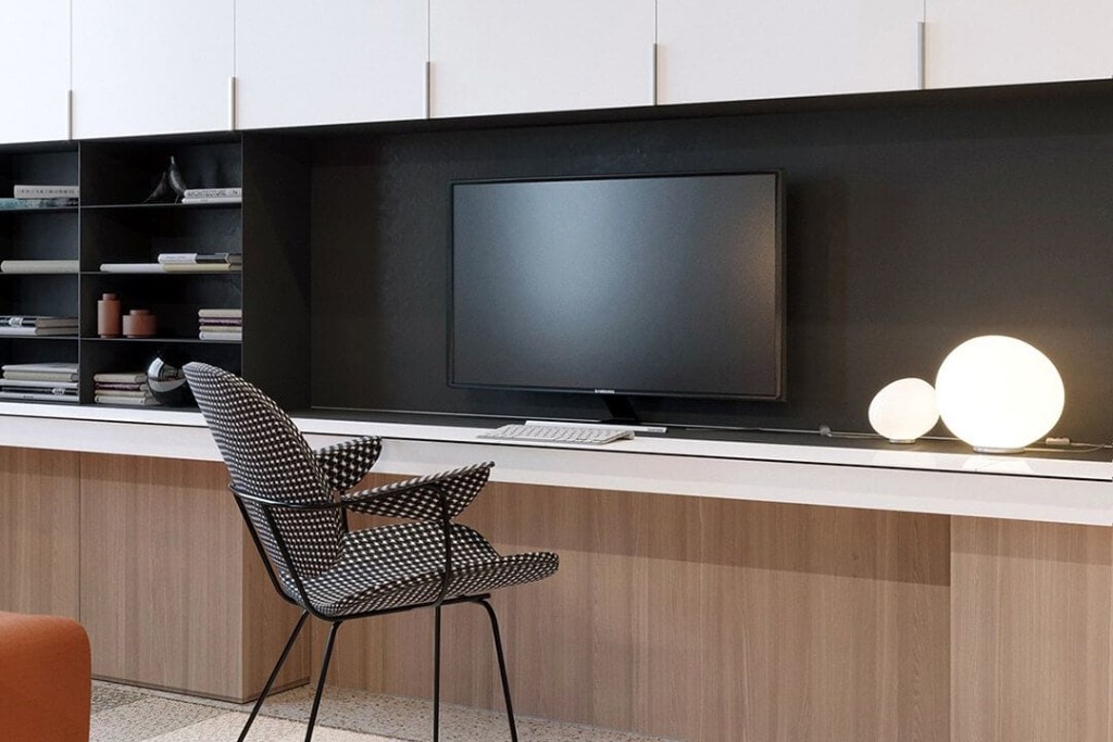 Luxury minimalist interior design of a narrow office desk with a large monitor wall mounted to the integrated wall storage in muted tri-coloured tones of natural wood, black and white