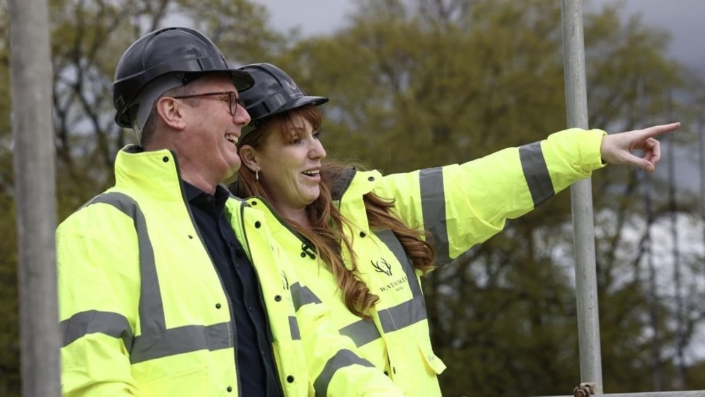 Angela Rayner and Keir Starmer in high-visibility jackets and hard hats smiling and pointing, likely discussing development or infrastructure projects within a Green Belt area.