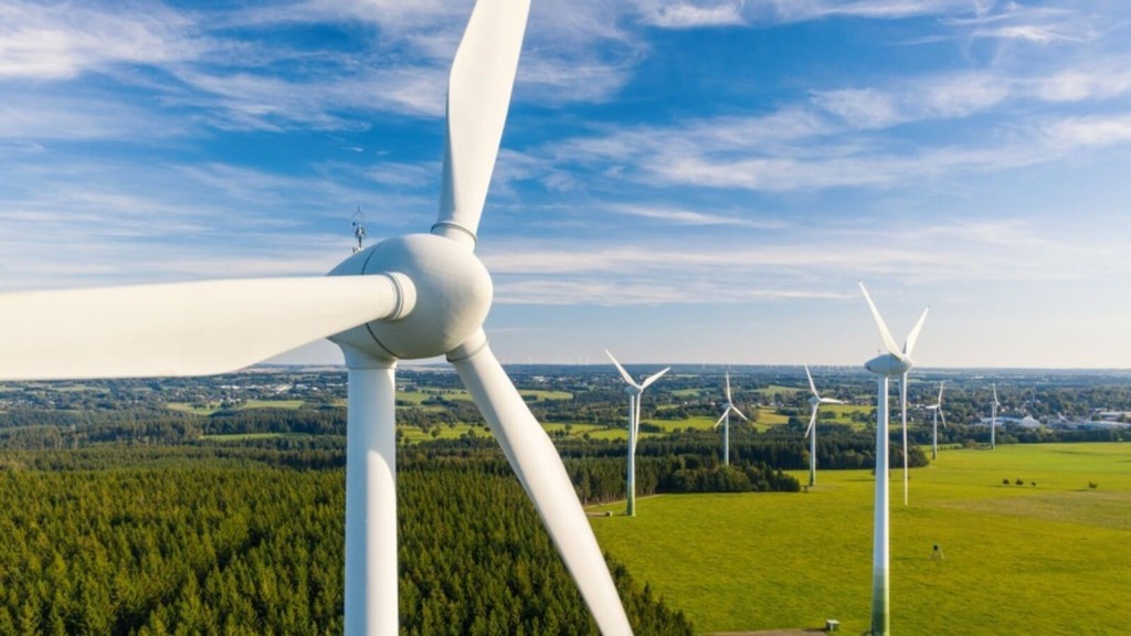 A wind farm in a Green Belt area, with turbines spread across open fields and forested land, symbolising sustainable energy solutions for data centres.