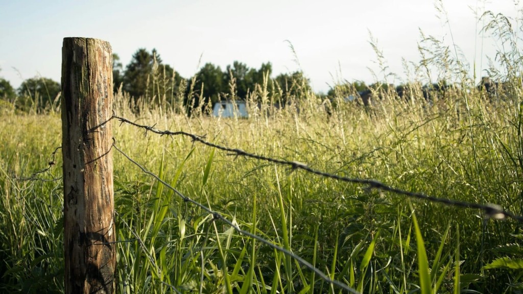 A close-up of a wooden fence post and barbed wire bordering a Green Belt field, representing the rural landscapes considered for data centre developments