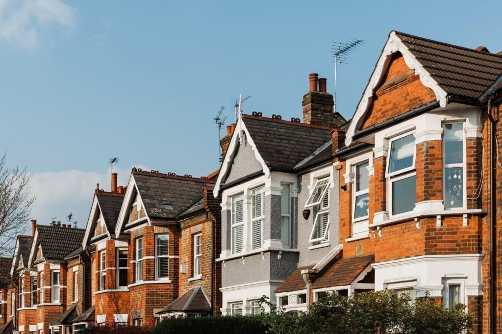 Row of traditional British terraced houses with distinctive red brickwork and gabled roofs, exemplifying classic urban residential architecture.