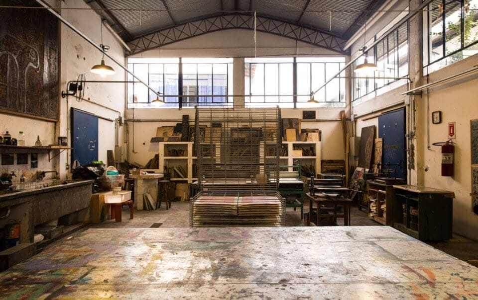 Interior of a vacant industrial workshop with high ceilings, large windows, and various tools and materials scattered around, suitable for redevelopment under permitted development rights. The space is characterised by its rustic charm and ample natural light, making it a potential site for conversion into residential flats or a single house without planning permission.