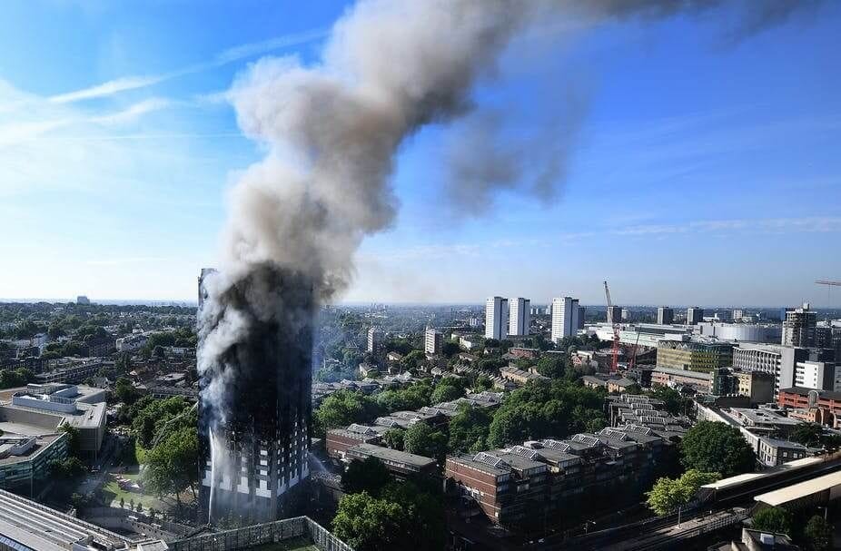 Firefighters battling a blaze at Grenfell Tower high-rise apartment complex with black smoke billowing into the sky, emphasising the urgency of fire safety measures in residential building design.