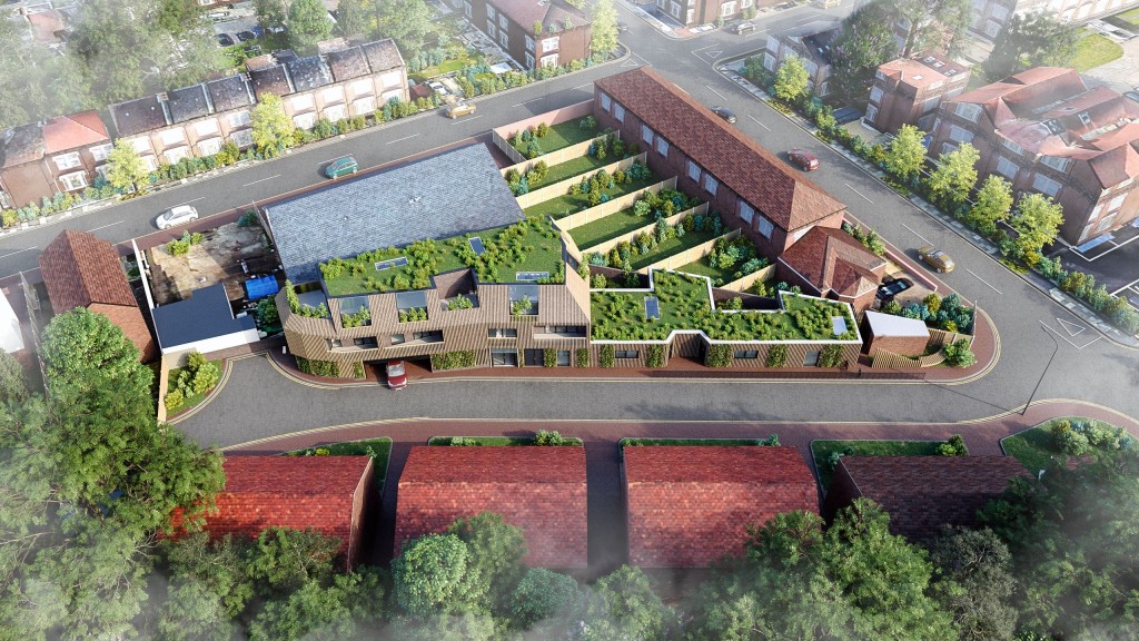 Aerial view of a modern small-site development of flats and townhouses featuring green roofs, landscaped courtyards, and surrounding urban residential areas, showcasing innovative use of space and sustainable design.