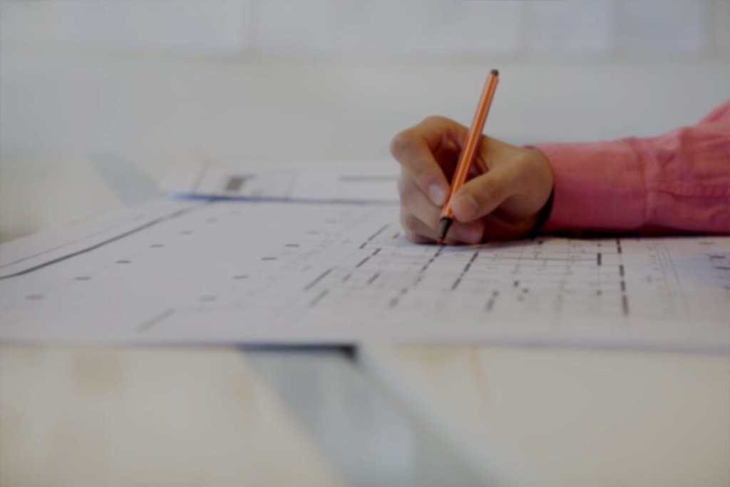 Professional hand holding a red marker pen to A3 printed construction detail drawings