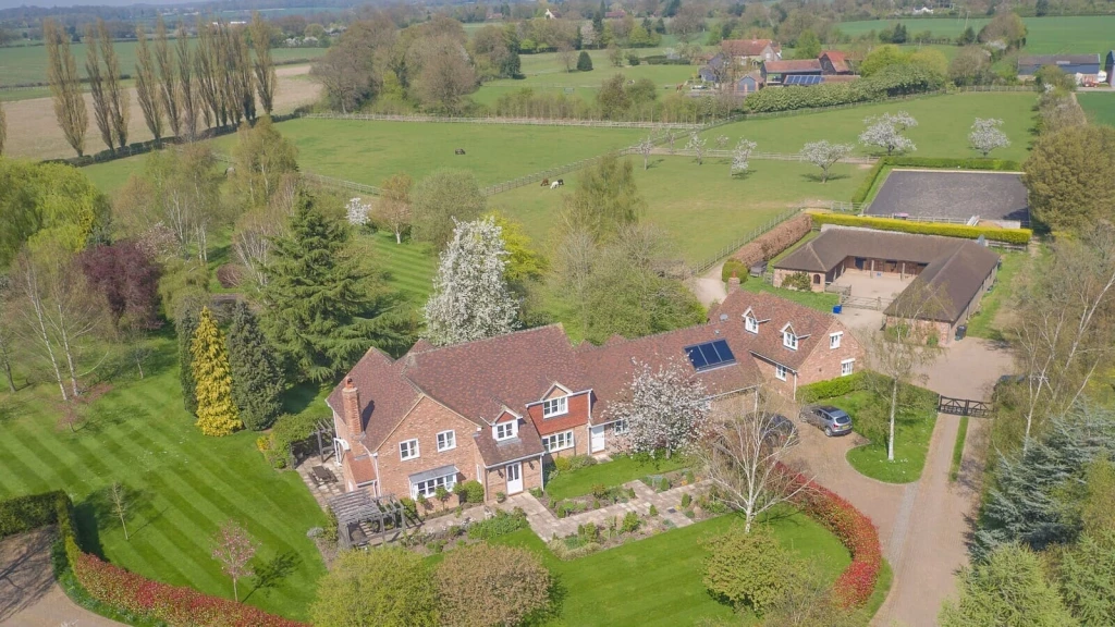 Aerial view of a rural house with landscaped gardens, paddocks and outbuildings, illustrating how domestic curtilage can change over time as the use, layout and relationship of land to the dwelling evolve.