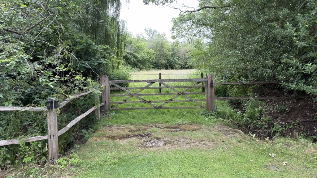 Wooden gate and fence separating a domestic garden from open land, illustrating why the domestic curtilage boundary should be established before relying on permitted development rights or designing a proposal.