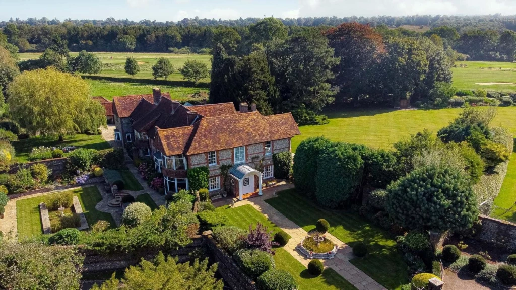Aerial view of a large rural house with formal gardens and surrounding open land, illustrating how an extensive domestic curtilage may affect permitted development calculations without making all adjoining land part of the curtilage.