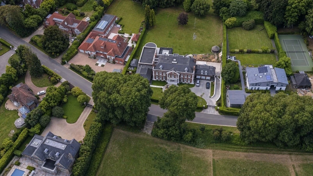 Aerial view of large detached houses with extensive gardens and grounds, illustrating how domestic curtilage may be narrower than the full area of land in a property’s ownership.