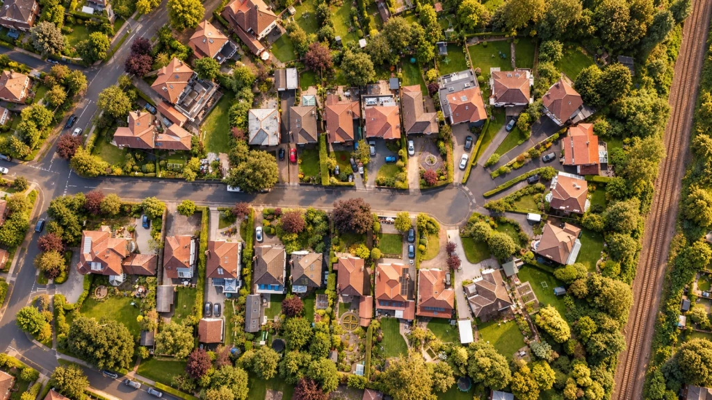 Aerial view of suburban houses, gardens and outbuildings illustrating how domestic curtilage relates to residential plots, boundaries and permitted development rights.