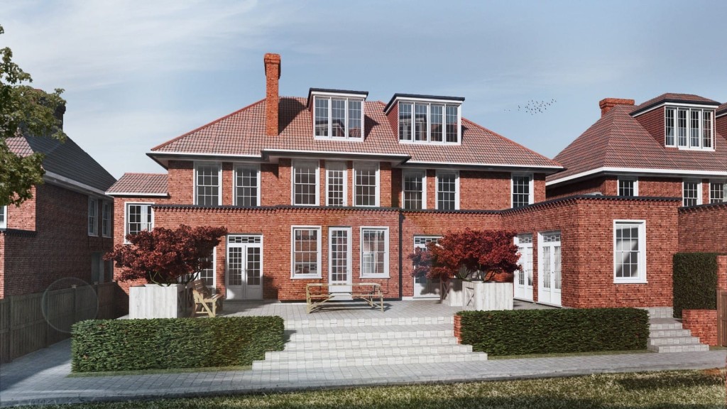 Elegant three-storey red brick house with tiled gable roof, dormer windows, and a spacious white-trimmed patio, surrounded by manicured hedges and mature trees, with a clear sky in the background.