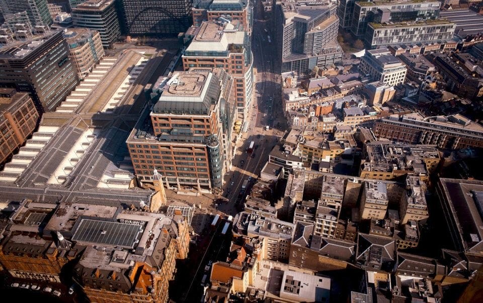 Aerial view of a dense urban area showcasing a mix of modern and traditional architecture with multiple buildings and rooftops, highlighting the complexity of city planning and development.