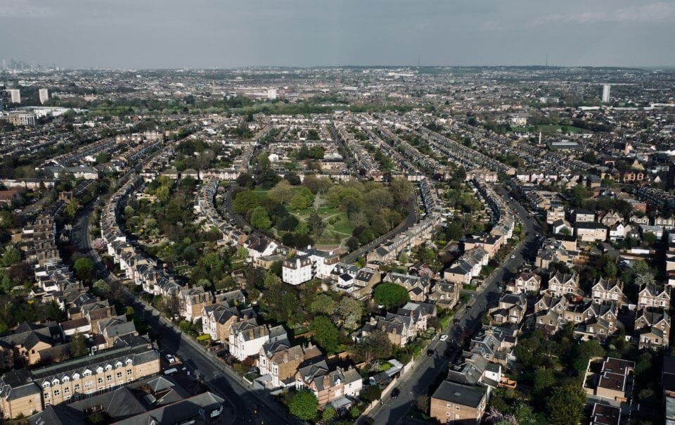 Aerial view of a London suburb showcasing residential houses surrounded by greenery and trees, emphasising the potential for upward extensions without planning permission. This image highlights the possibilities for expanding homes vertically, adhering to the Town and Country Planning (General Permitted Development) rules. Ideal for those considering property development and home improvements in the UK, particularly in urban and suburban areas.