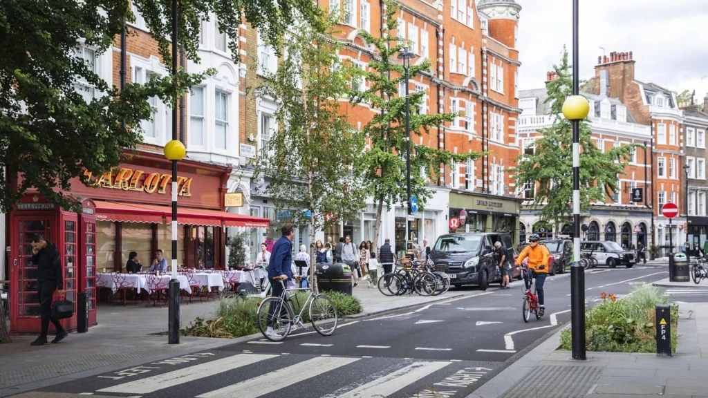 London high street with shops, restaurants, pedestrians, cyclists and traditional architecture, showing how high street regeneration can add choice while preserving local character.