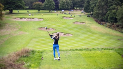 Golfer teeing off on a lush green course within a green belt area, reflecting the debate around using golf course land for housing development as part of green belt reform.