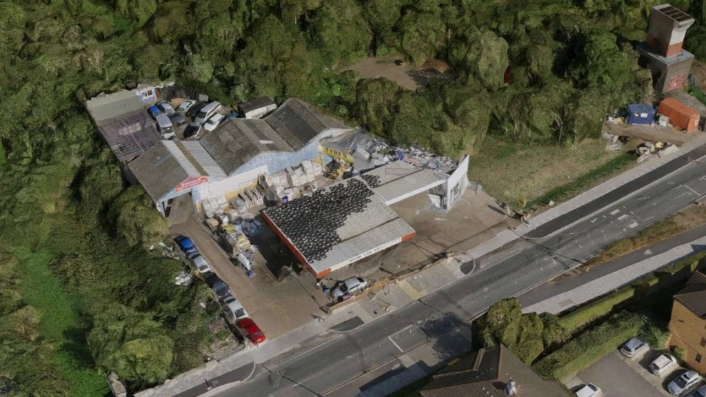Aerial view of roadside garage, MOT testing centre, and tyre depot in Tottenham (N17) on the Green Belt edge, with stacked tyres, low workshops, and commercial vehicles.
