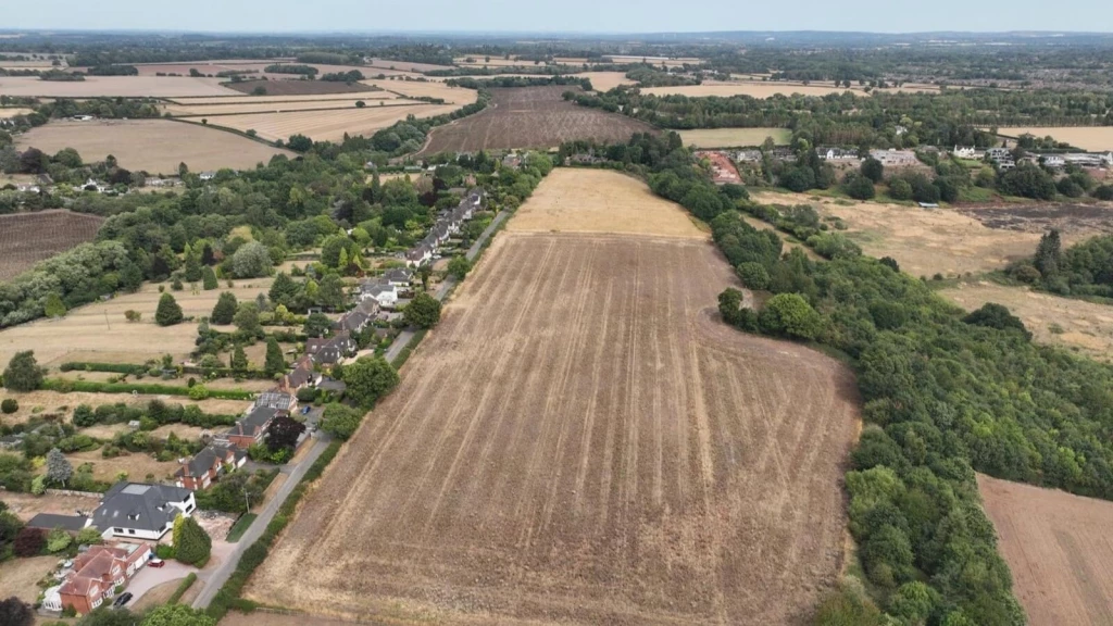 Aerial view of open countryside farmland adjoining a small village settlement, illustrating concerns around inappropriate development in the Green Belt, assessing planning applications in the Green Belt, and the potential effects on the openness of the Green Belt through encroachment.