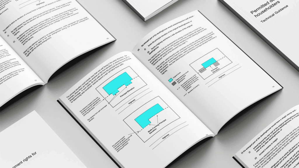 Technical guidance booklet open on a table displaying diagrams and text on permitted development rights for householders, highlighting zoning and property extension regulations.