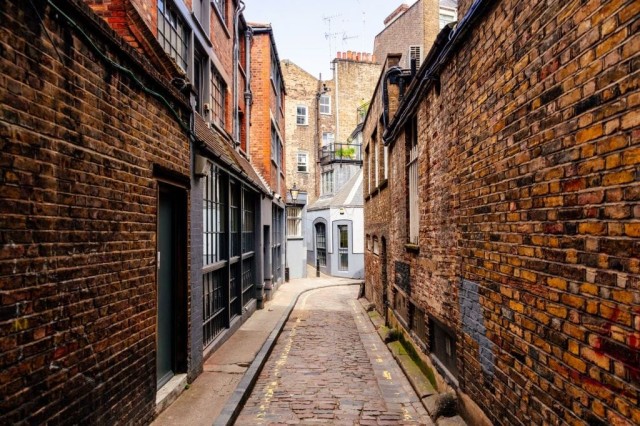Image cover for the article: Street view of two beautiful red brick listed properties in central London with an arched access to the white front doors with gold door knobs, gold letter box and gold kick plate