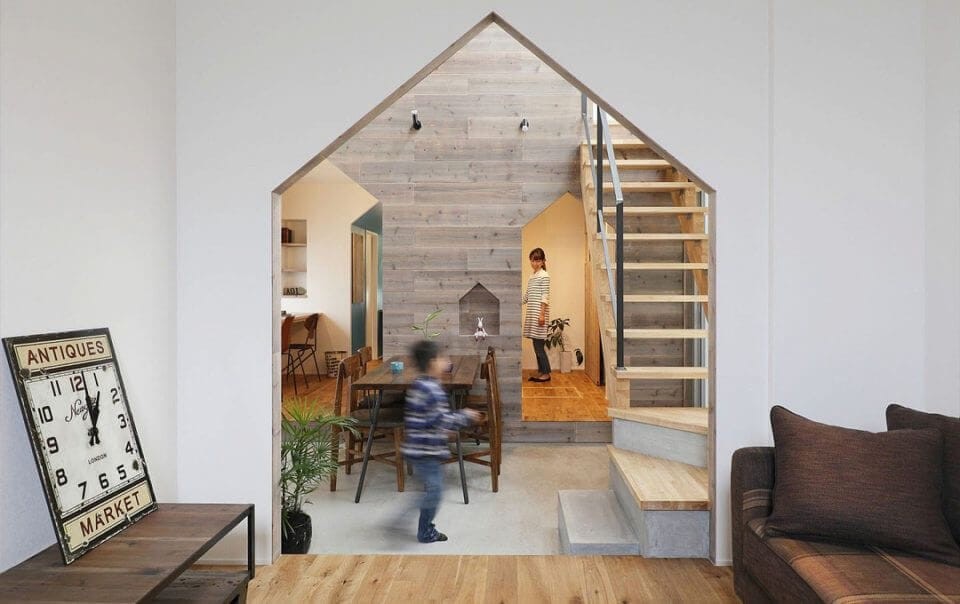 Modern barn house interior design of the liviing room leading directly onto the formal dining room and kitchen through large pentagon shaped entrance ways and also the use of natural wood panneling on the walls and exposed wood flooring and natural wooden staircase