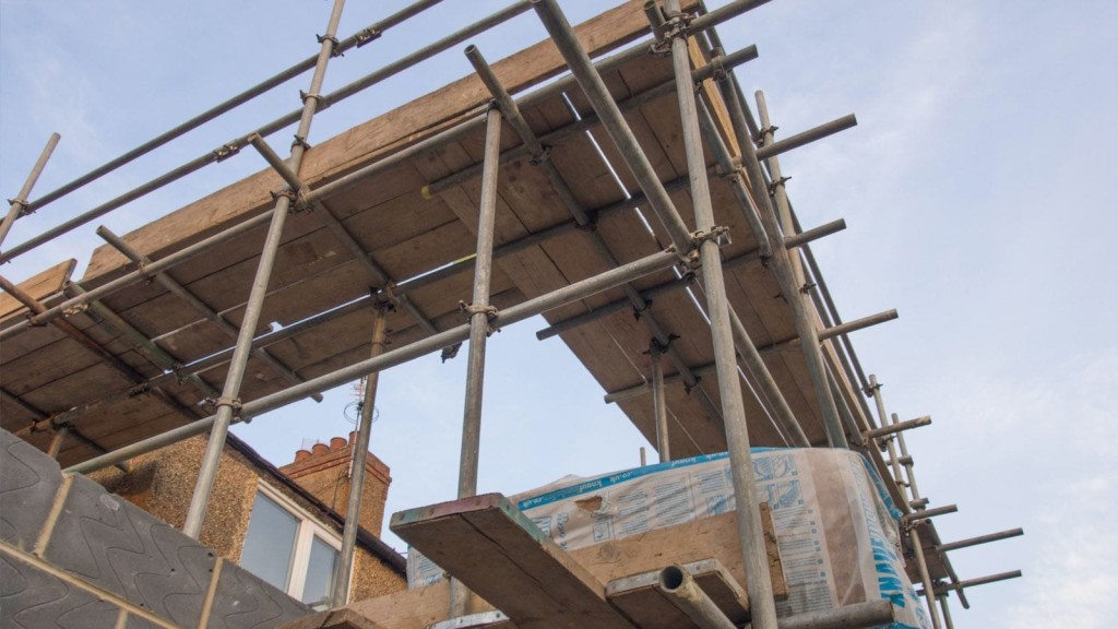 Scaffolding setup for a house extension project in London, illustrating the initial stages of construction. The image highlights the structural framework and materials needed for building a home extension, emphasising the importance of proper planning and budgeting for construction costs.