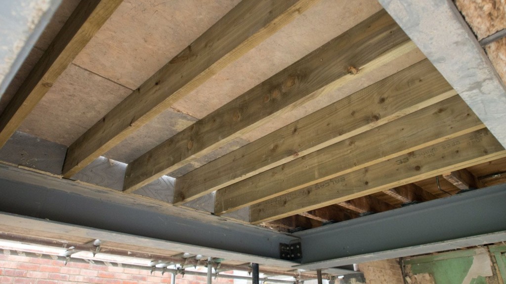 Close-up view of wooden beams and steel supports in the construction of a house extension in London. The image highlights the structural framework and essential materials used in building a sturdy home extension, emphasising the importance of quality construction and detailed planning for successful home renovation projects.