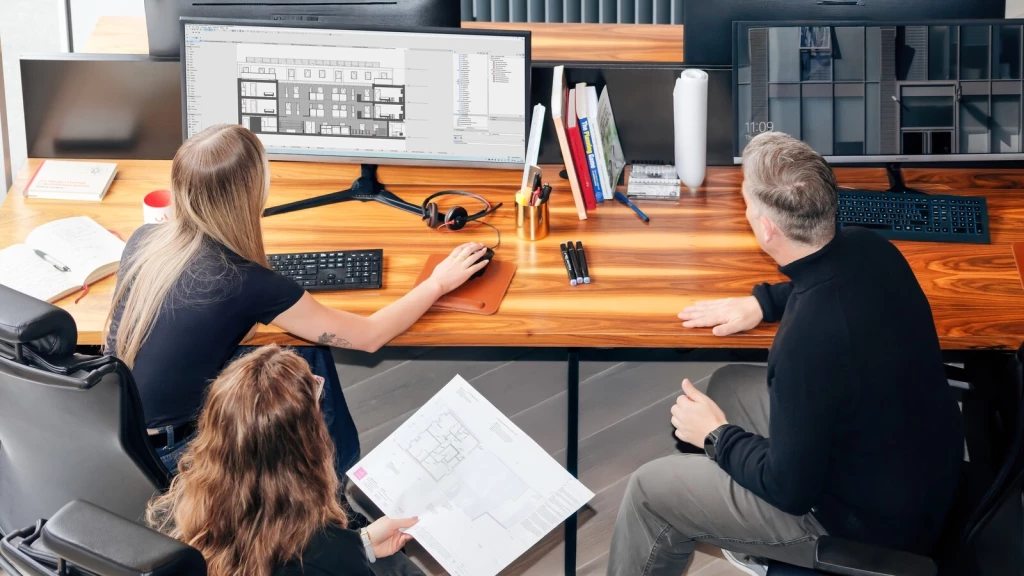 Residential architects and planning consultants at Urbanist Architecture reviewing architectural elevations and floor plans together in the studio.
