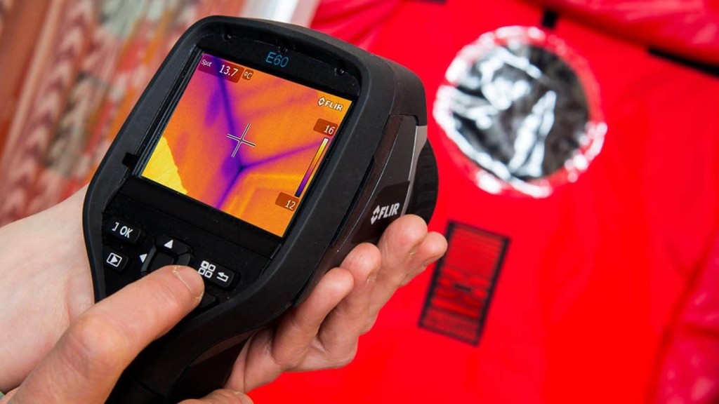 Technician using a thermal imaging camera to conduct an airtightness test in a building, identifying areas of heat loss. The image highlights the importance of achieving high levels of airtightness in eco, Passivhaus, and zero-carbon houses to improve energy efficiency and reduce heating requirements.