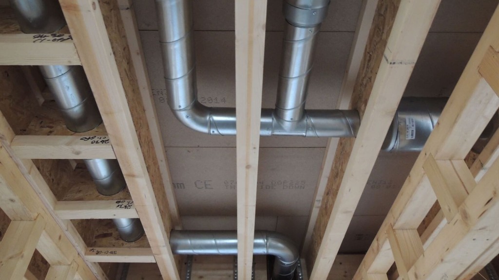 View of mechanical ventilation system ducts installed in the ceiling of an eco house under construction. The image highlights the importance of mechanical ventilation and heat recovery (MVHR) systems in maintaining indoor air quality and energy efficiency in Passivhaus and zero-carbon homes.