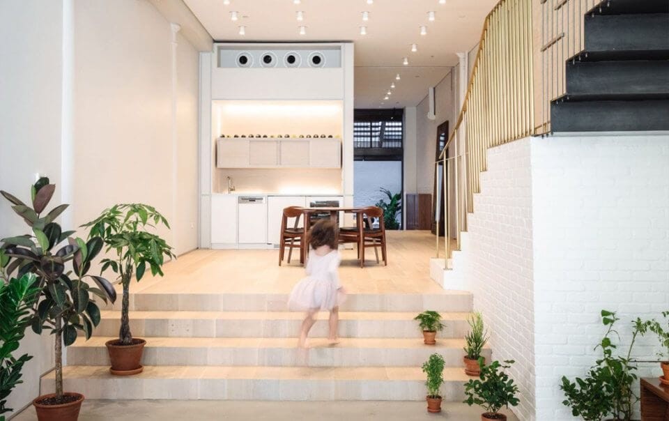 Bright and spacious ground floor extension idea with light beige marble floor, gold stair railing and many ceilling spotlights allowing for a blurry running little girl to enjoy and play in this additional space