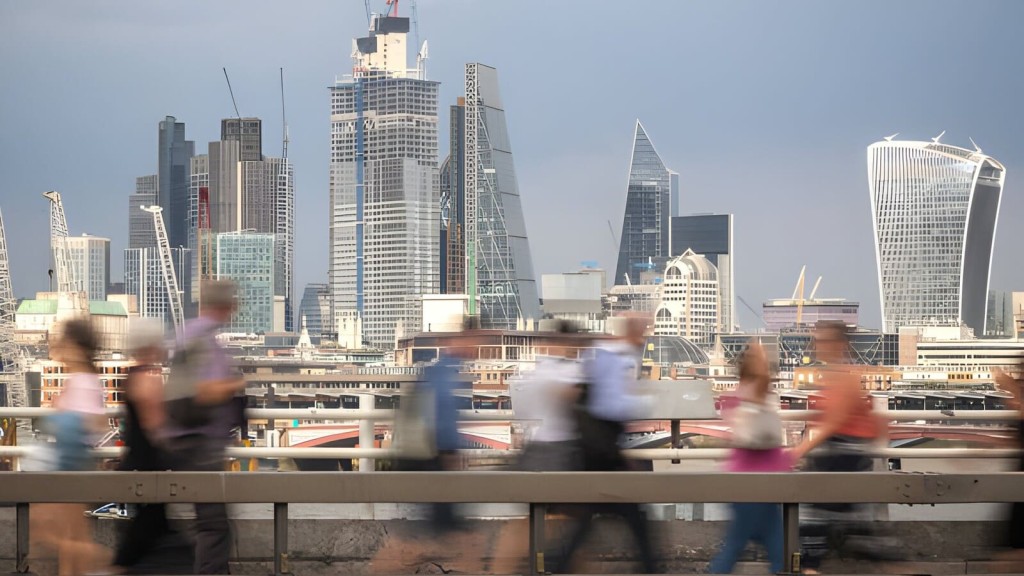 Motion-blurred pedestrians crossing a bridge with a clear view of London's dynamic skyline in the background, featuring iconic skyscrapers under construction, symbolising the fast-paced growth and housing crisis in urban UK settings.