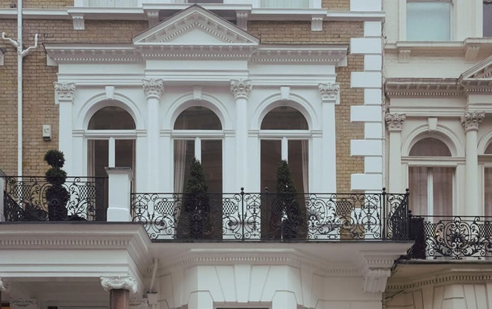 Ornate Victorian facade of a Grade II listed building in London, featuring intricate cornicing, arched windows with white trim, and elegant wrought-iron balcony railings.