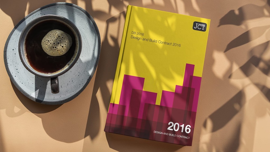 A cup of black coffee next to the JCT Design and Build Contract 2016 book on a terracotta surface, highlighting resources for construction project management.